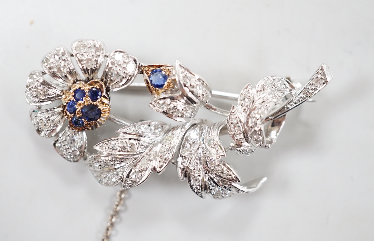 A modern white metal, sapphire and diamond chip set floral spray brooch, 43mm, gross weight 8.8 grams.